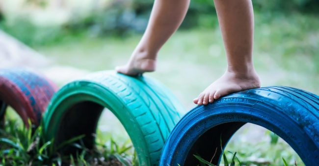 Child playing with tires in a playground